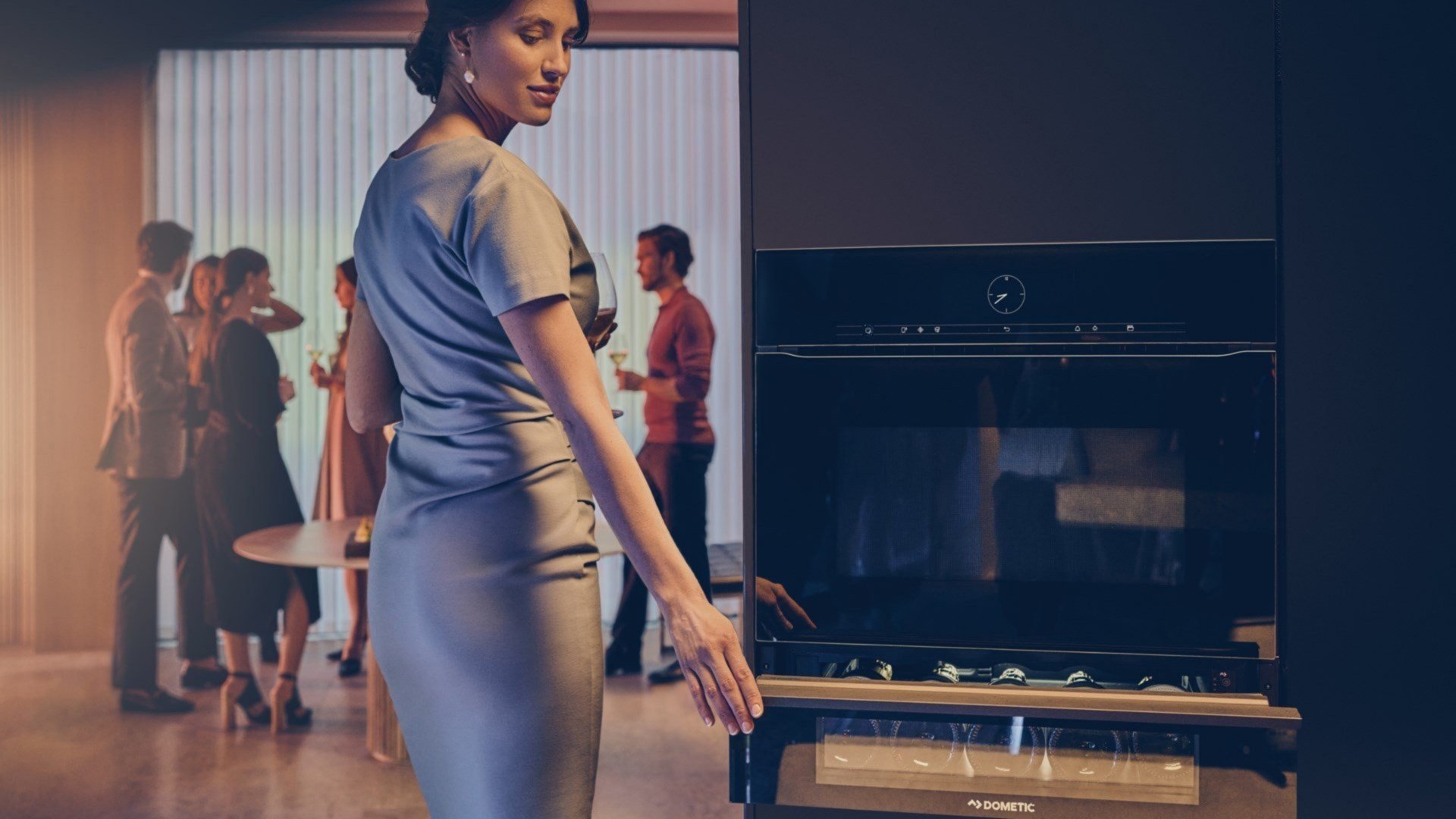 A woman at a party closing a wine drawer.