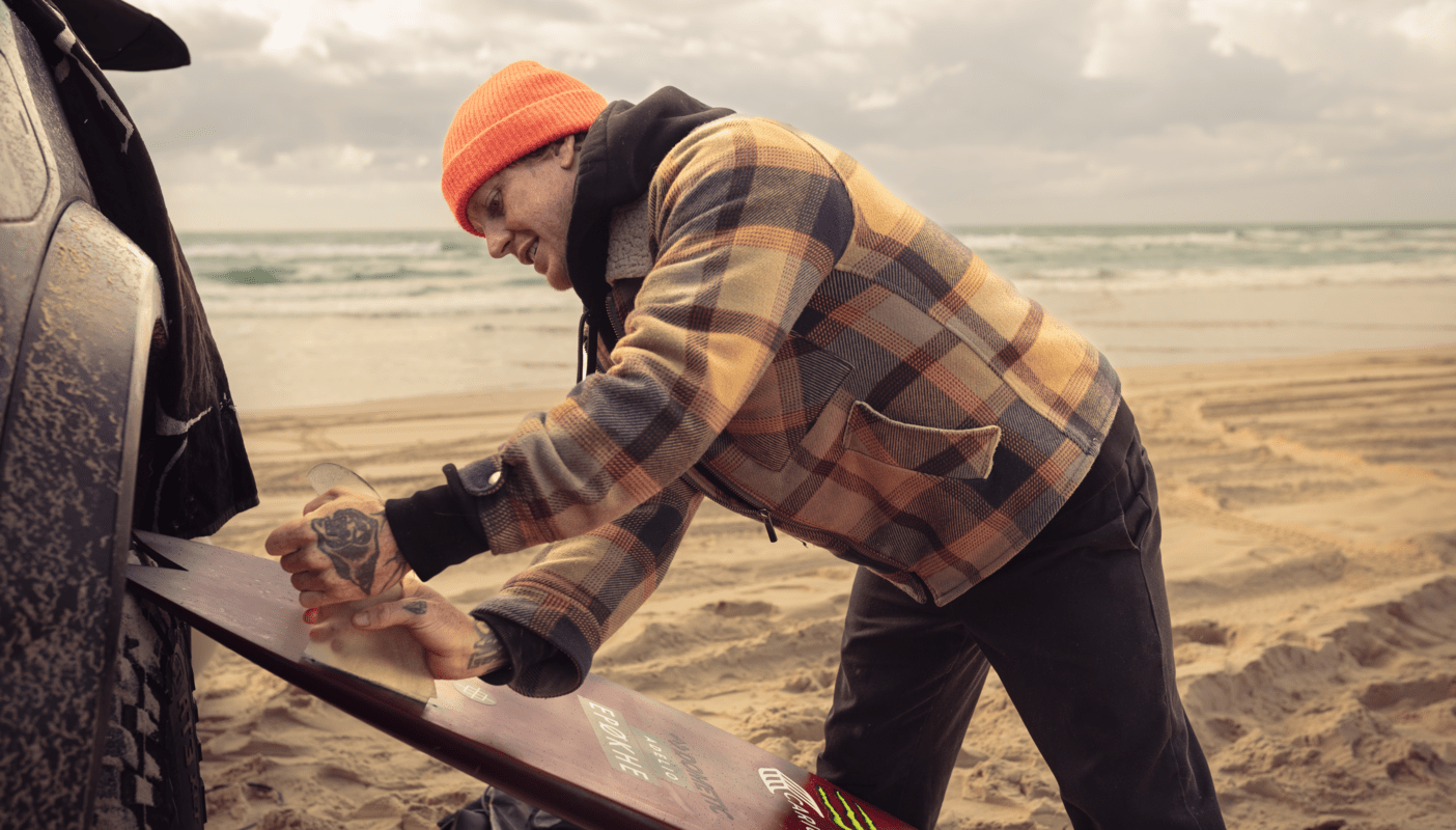 Chippa Wilson waxing his surfboard