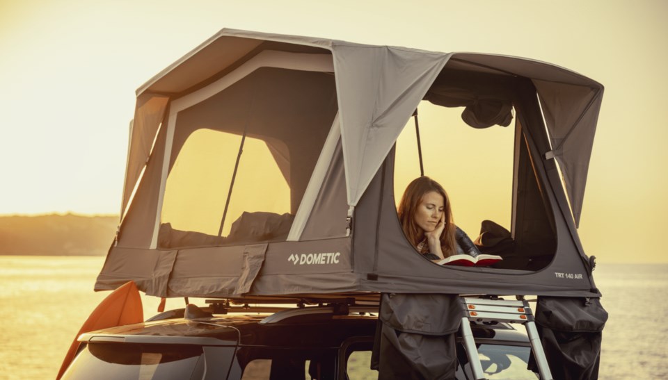 Woman reading in Dometic rooftop inflatable tent.