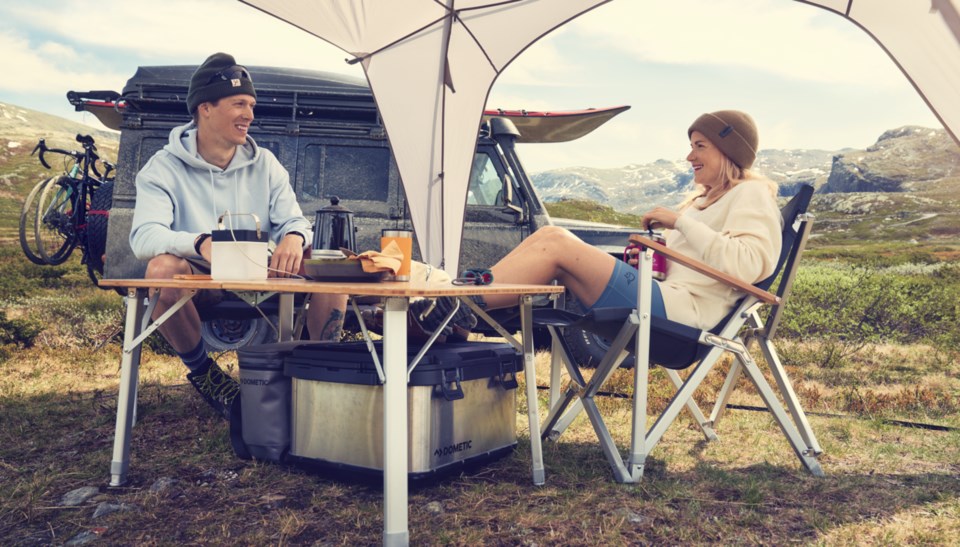 couple sitting at camp table snacking and relaxing.
