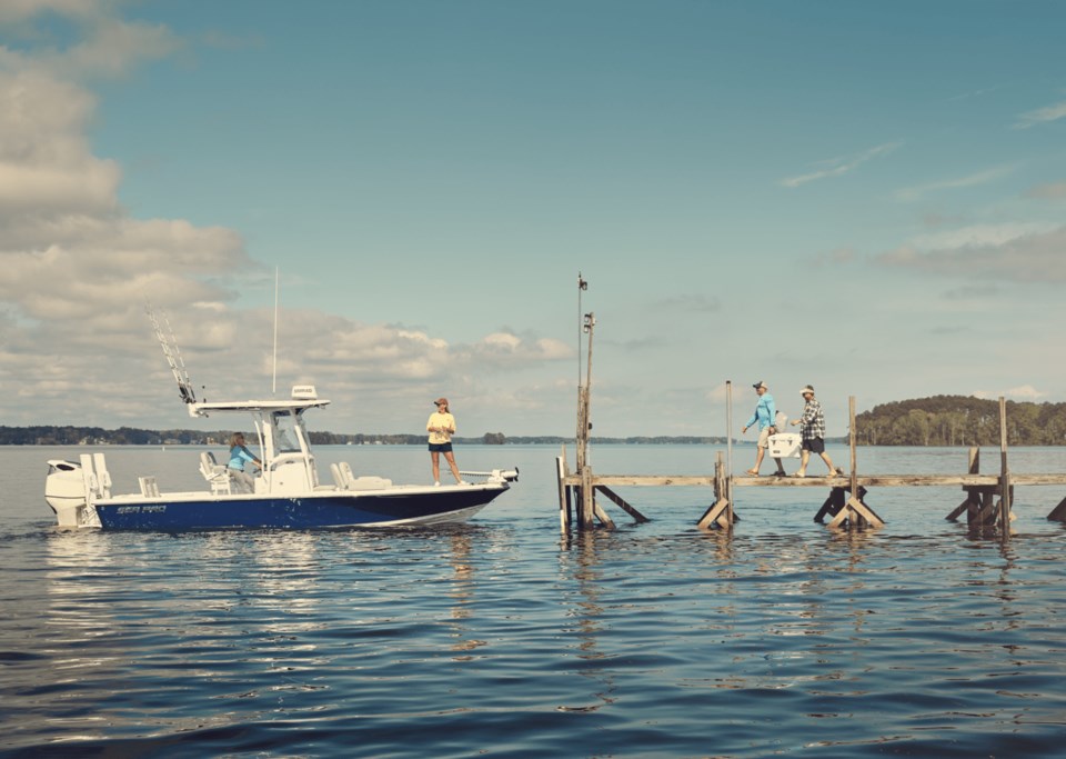 A small boat pulling up to a dock to pick people up.