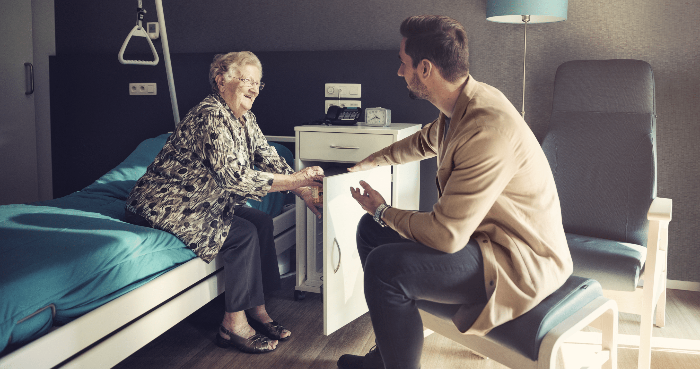 Nurse and elderly man smiling at eachother in a care room