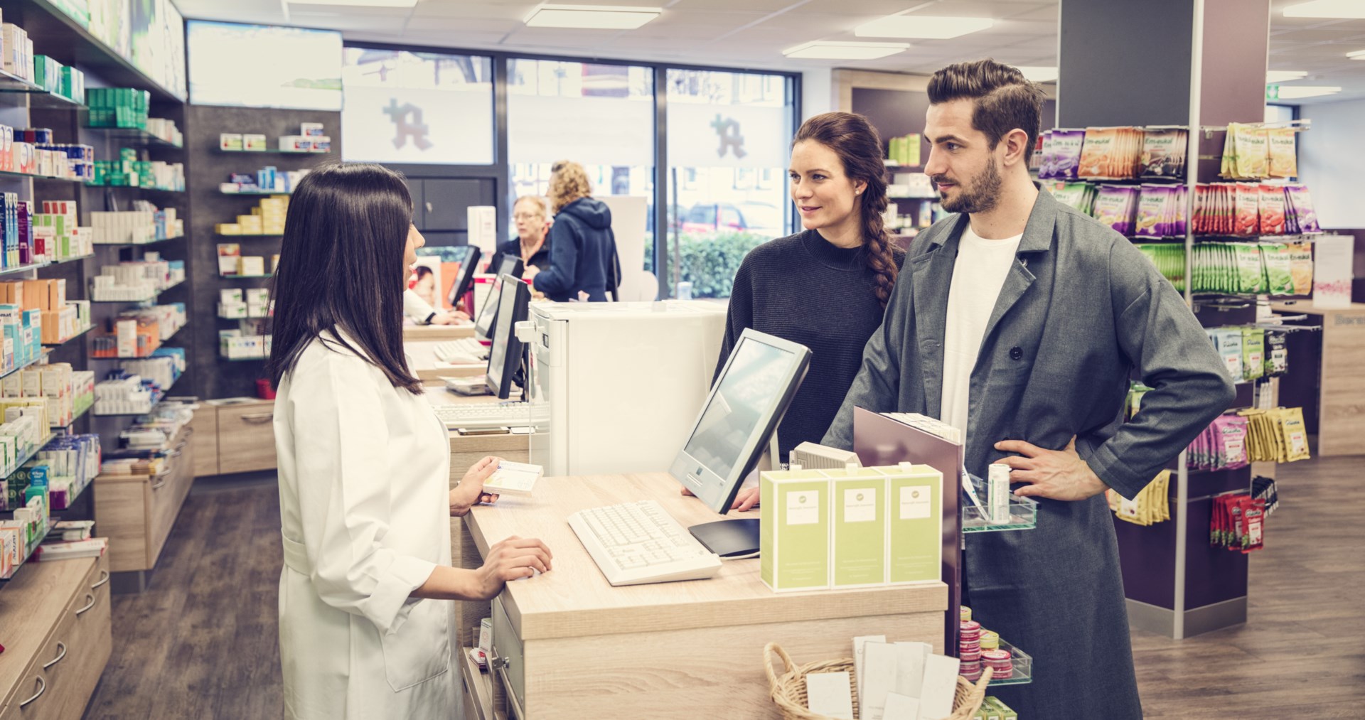 Man en vrouw praten met een apotheker bij de kassa