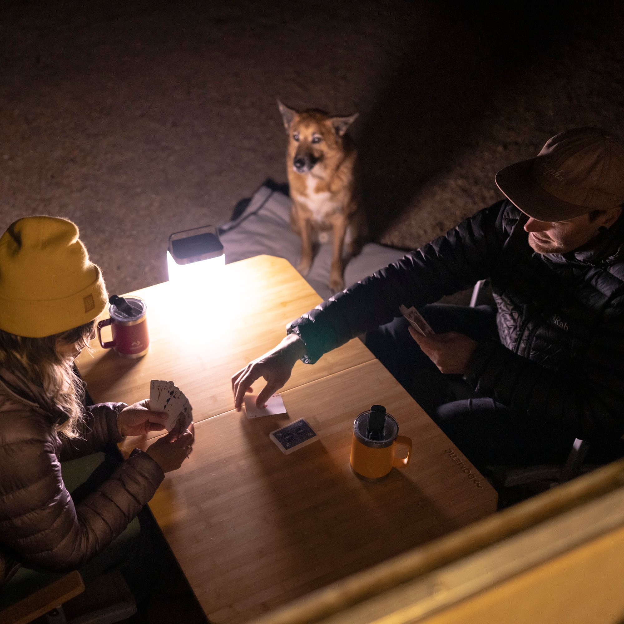 couple sitting outside at night with light while off grid camping